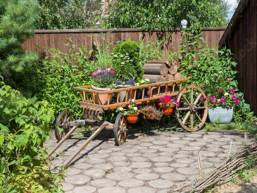 Decorative vintage cart in the garden. Landscaping. Summer sunny day