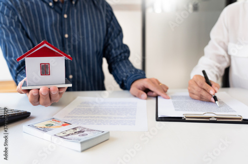 Sale representative offer house purchase contract to buy a house or apartment or discussing about loans and interest rates.