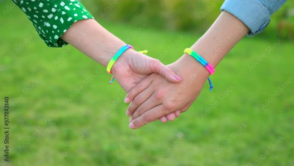 Two homosexual woman couple holding hands outdoors. with rainbow lgbt symbol gay pride - lesbian, gay, bisexual, transgender. Concept of happiness, freedom, love same-sex couple, 4 K slowmo Two homosexual woman couple holding hands outdoors. with rainbow lgbt symbol gay pride - lesbian, gay, bisexual, transgender. Concept of happiness, freedom, love same-sex couple, 4 K slowmo