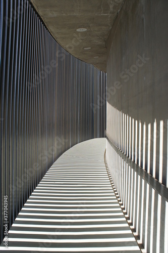 Metal bars casting shadows on a concrete walkway.