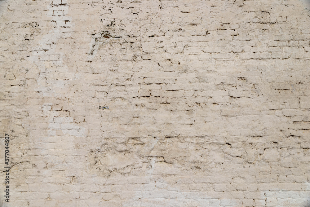 The texture of the old brick wall painted white with peeling paint