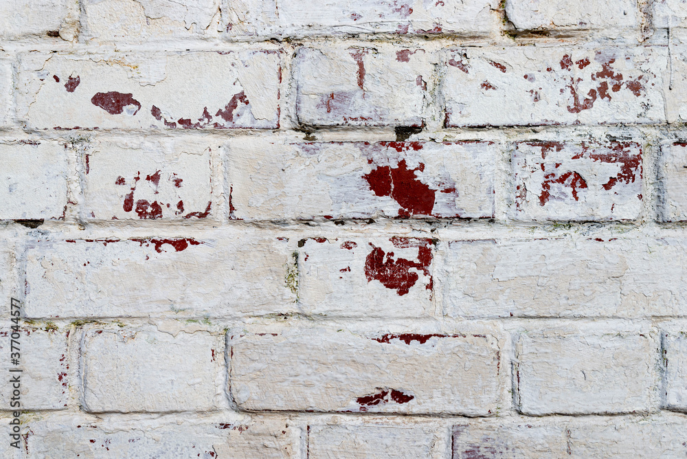 The texture of the old brick wall painted white with peeling paint