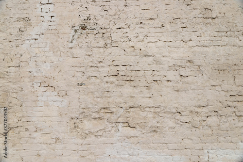 The texture of the old brick wall painted white with peeling paint