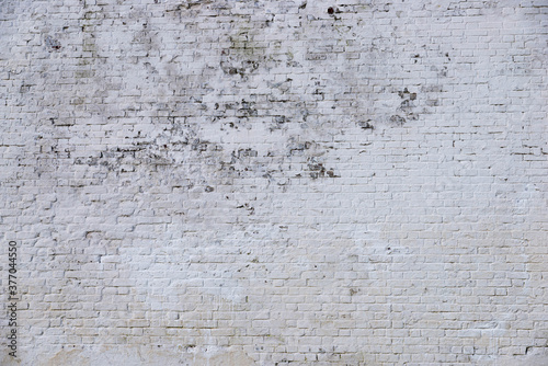 The texture of the old brick wall painted white with peeling paint