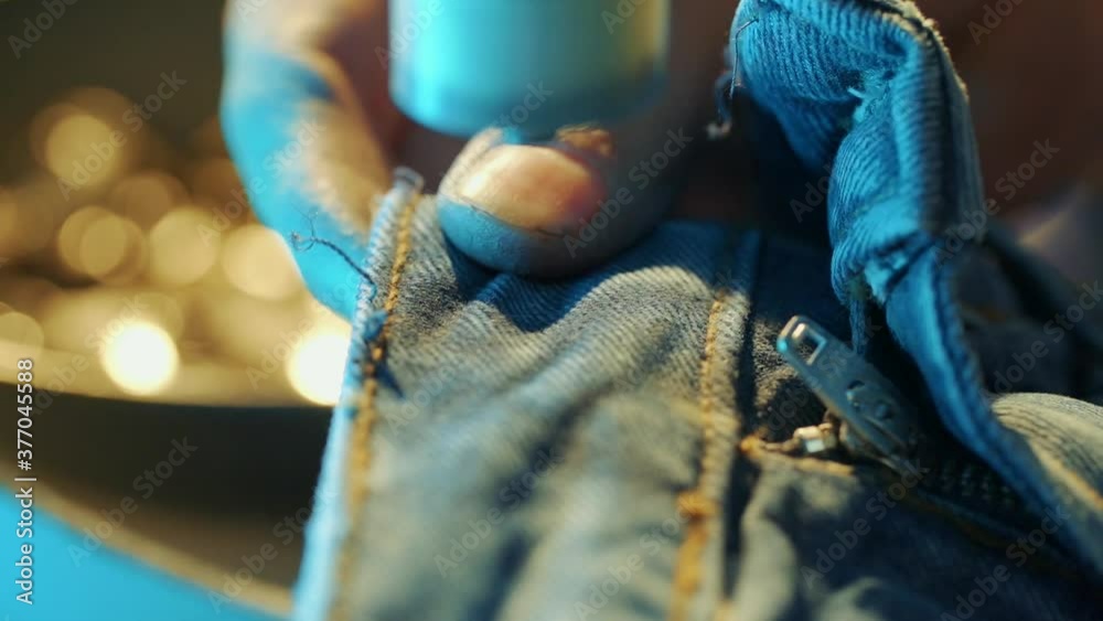 worker in jeans factory pushes button on jeans on the machine.