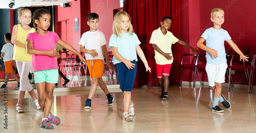 Group of smiling little boys and beautiful girls having a dancing class in studio