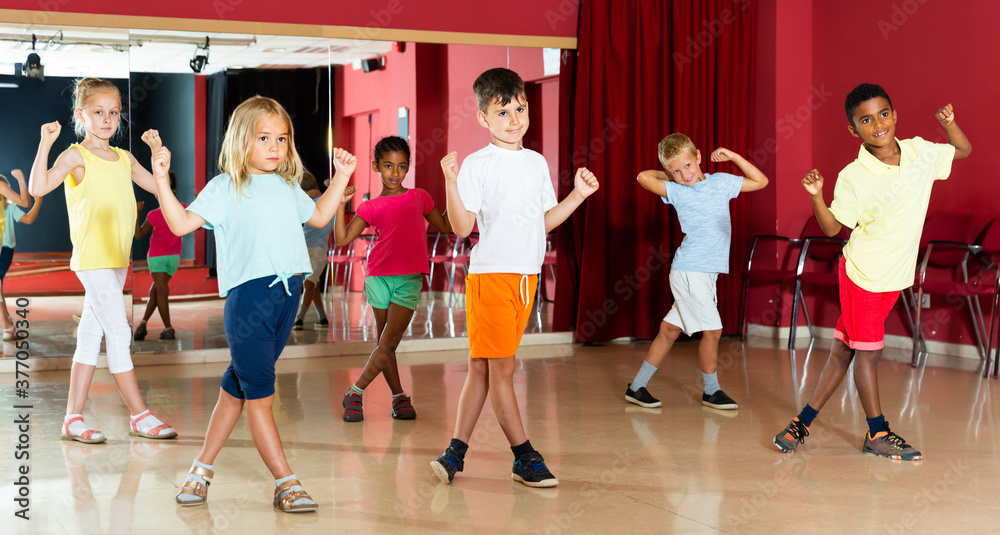 Glad kids trying balance movements of ballet in classroom