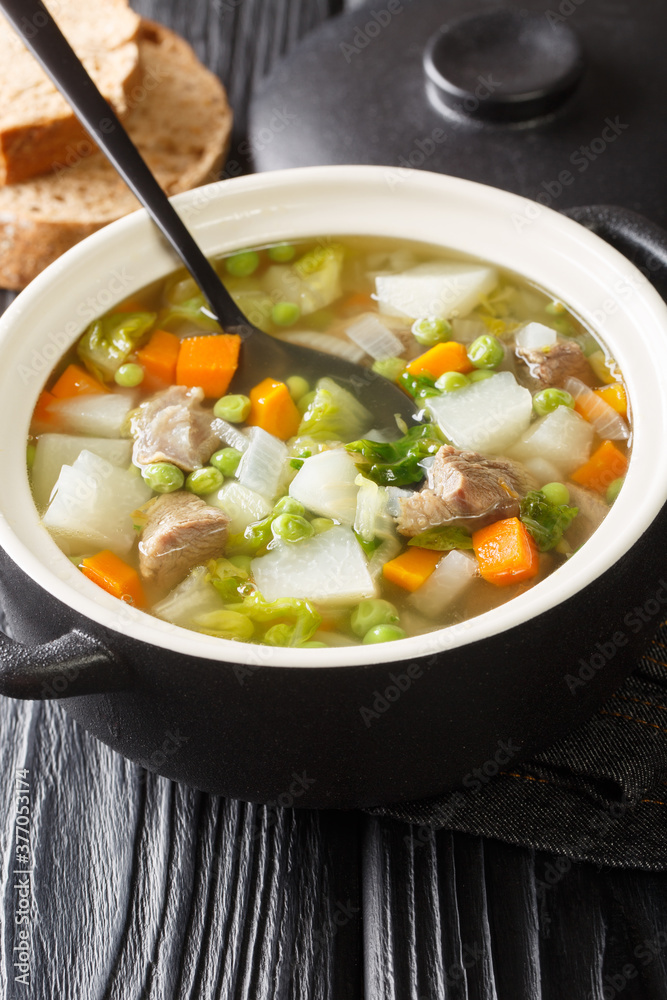 Hairst Bree is a hearty Scottish bowl of Harvest Broth or Hotch Potch close-up in a pot on the table. Vertical