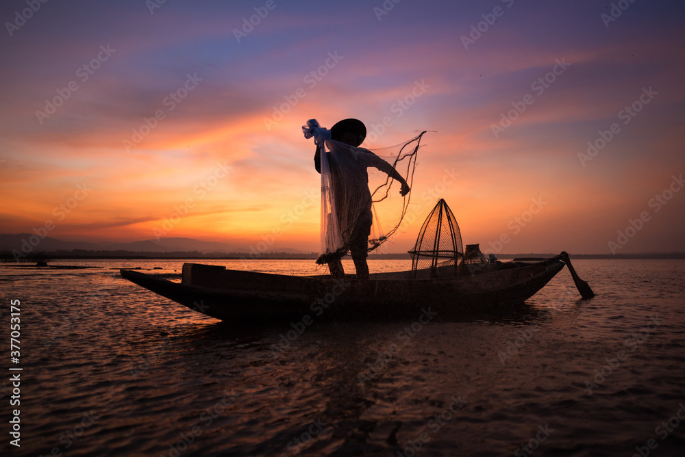 Asian fisherman with his wooden boat in nature river at the early morning before sunrise