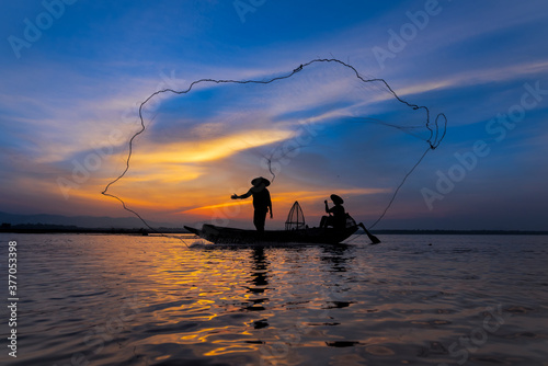 Asian fisherman with his wooden boat in nature river at the early morning before sunrise