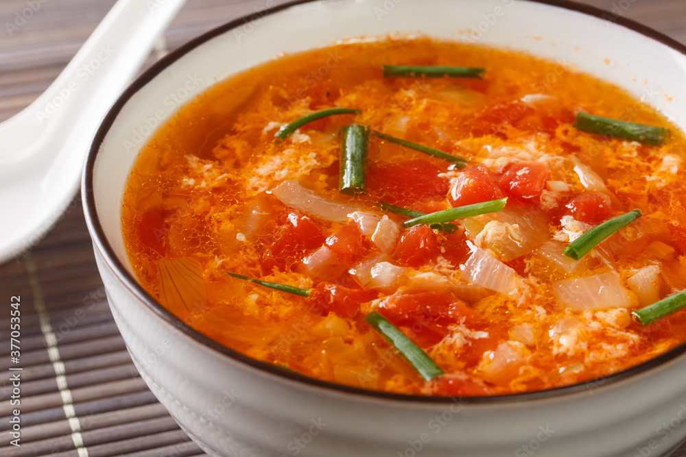 Easy Tomato Egg Drop Soup or egg flower soup close-up in a bowl on the table. Horizontal Easy Tomato Egg Drop Soup or egg flower soup close-up in a bowl on the table. Horizontal