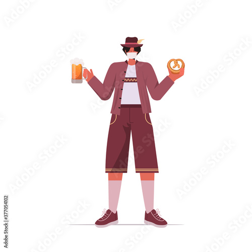 man in medical mask holding salty pretzel and beer mug Oktoberfest party celebration coronavirus quarantine concept guy in german traditional clothes full length isolated vector illustration