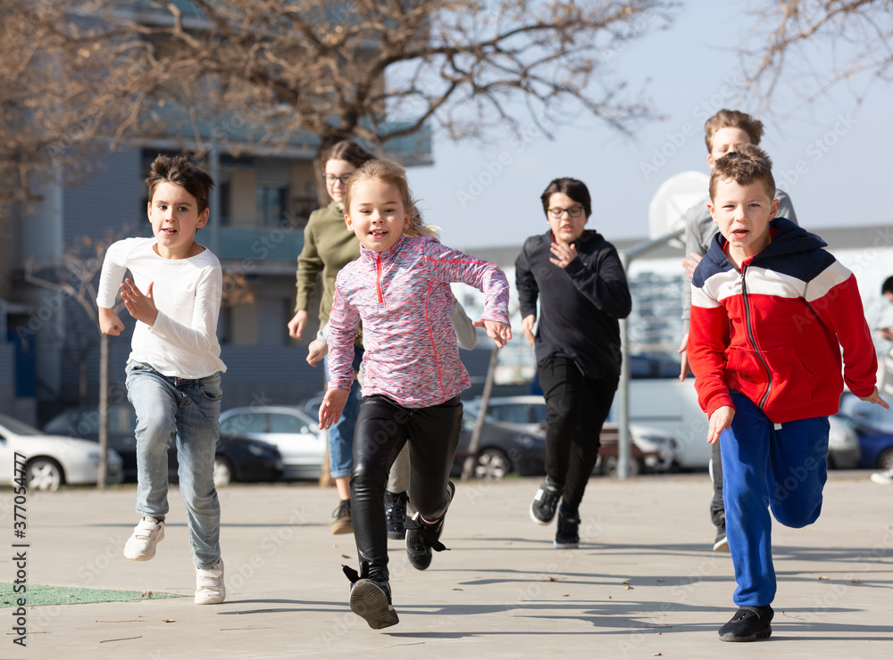 Fototapeta premium Kids spending time together outdoors running on square at warm spring day