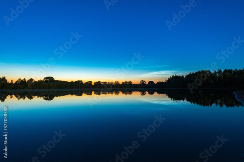 Fototapeta Naklejka Na Ścianę i Meble -  Leuchtende Nachtwolken über einem See in Deutschland