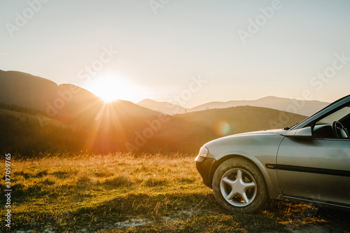 Travel concept with the car against sunset and mountains. Close Up photo of the wheel. © Serhii