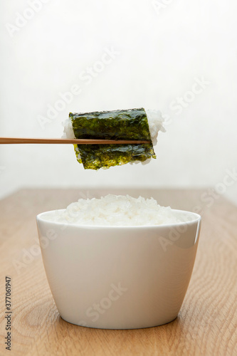 chopstick holding boiled rice wrapped with seasoned laver photo