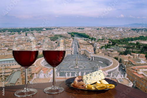 Photography Two glasses of red wine with assortment of cheese and meat against view of Saint Peter's Square in Vatican, Rome, Italy