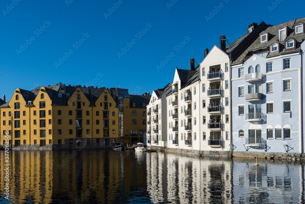 Beautiful old stone houses with art nouveau facades directly on the waterfront in Ålesund on a clear sunny winter day