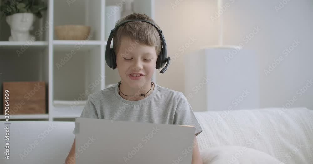 carefree boy is talking online by web camera with friends or family, sitting on couch at home carefree boy is talking online by web camera with friends or family, sitting on couch at home