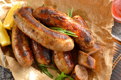 Grilled sausages. Bavarian sausages with herbs and rosemary. Food on parchment. Close-up. Gray background.