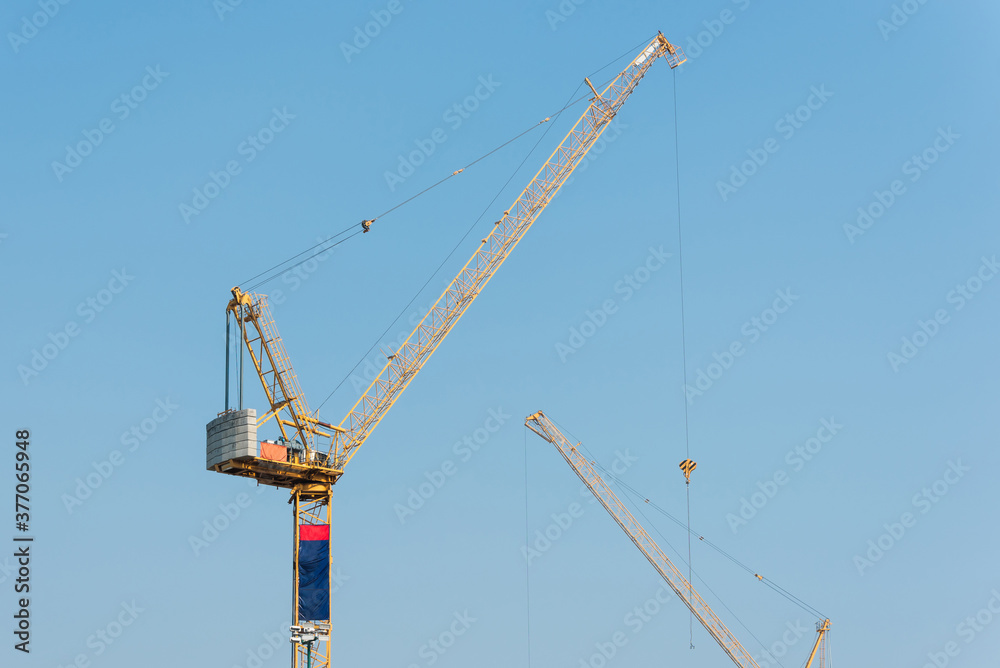 Industrial construction cranes at construction site with clear sky background