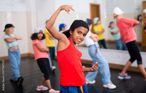 Cheerful preteen girls and boys hip hop dancers doing dance workout with female trainer during group class