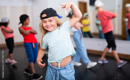 Fototapeta Naklejka Na Ścianę i Meble -  Portrait of emotional girl doing hip hop movements during group class in dance studio