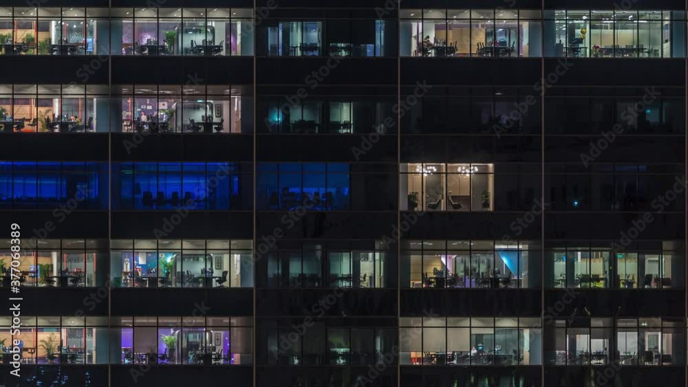 Modern office building with big windows at night timelapse close up view, in windows glowing light shines and some people inside, Singapore. Pan left Modern office building with big windows at night timelapse close up view, in windows glowing light shines and some people inside, Singapore. Pan left