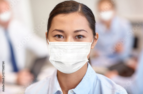 business, people and pandemic concept - businesswoman wearing face protective medical mask for protection from virus disease at office