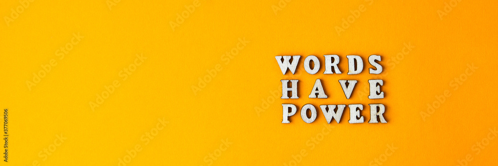 Quote WORDS HAVE POWER made out of wooden letters on bright yellow background.