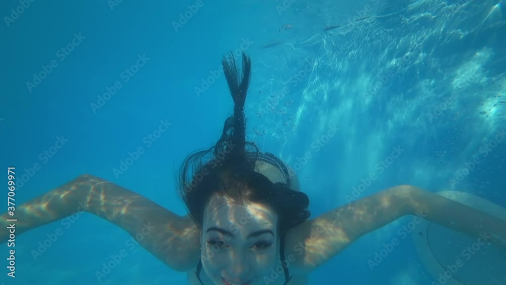 summer rest, pretty smiling female relish swimming in pool and diving during happy weekend at resort, shooting underwater