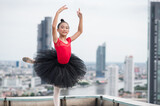 Asian ballerina girl dancing on the rooftop of the building city background.