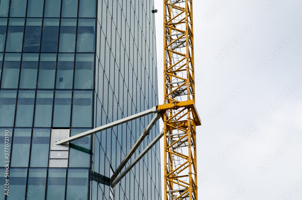 scaffolding in architecture, skyscraper with crane for construction site work with supported structure. Steel lattice structure support modules for glass and crystal building. web news scaffolding in architecture, skyscraper with crane for construction site work with supported structure. Steel lattice structure support modules for glass and crystal building. web news