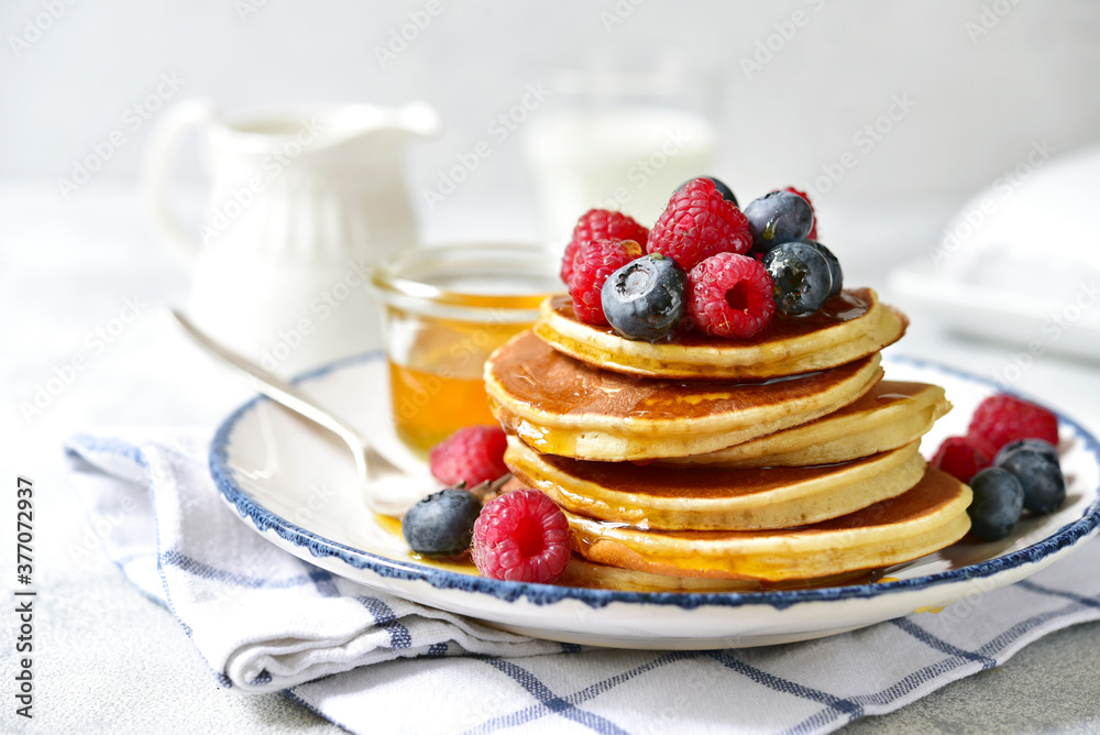 Hot banana pancakes with fresh berries and honey for a breakfast.