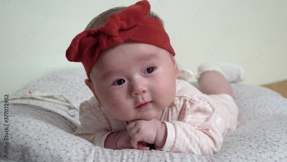Newborn infant baby girl lying on belly supporting her head with hands, back and neck training Newborn infant baby girl lying on belly supporting her head with hands, back and neck training