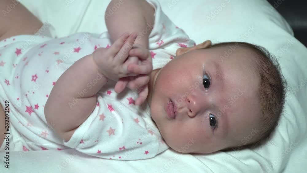 Side out from Newborn infant baby girl playing with her hands on the bed Side out from Newborn infant baby girl playing with her hands on the bed