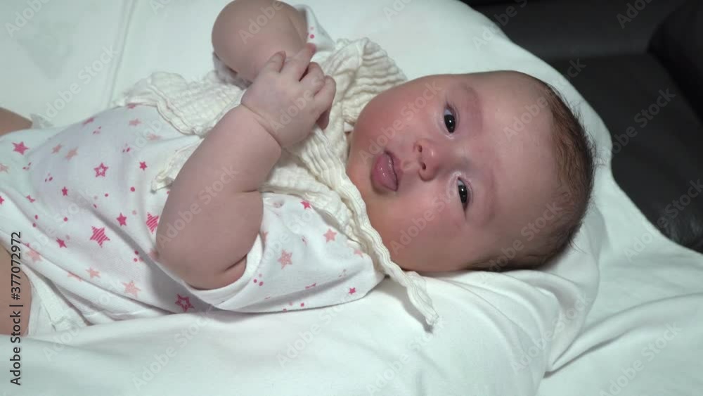 Newborn infant girl playing with her hands and touching face because feel sleepy Newborn infant girl playing with her hands and touching face because feel sleepy