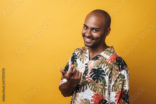 Image of smiling african american guy beckoning someone