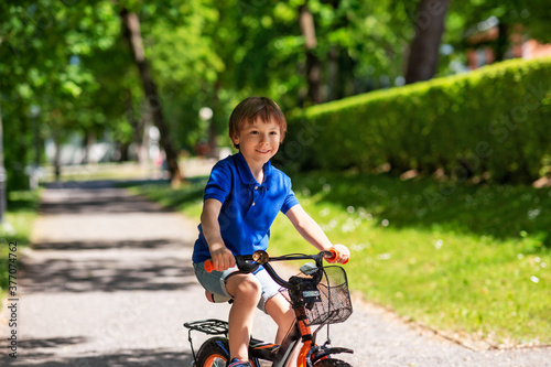 childhood, leisure and people - happy smiling little boy riding bicycle at summer park