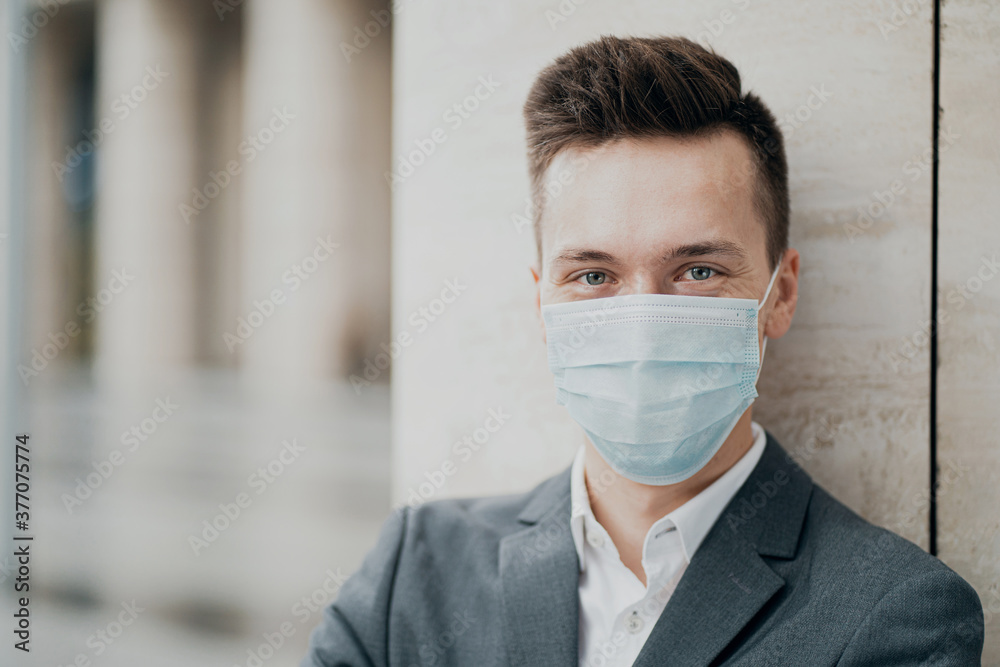 portrait of a business man businessman, wearing a protective mask of blue color from the pandemic, coronavirus, virus and other air diseases. looking at the camera, background city portrait of a business man businessman, wearing a protective mask of blue color from the pandemic, coronavirus, virus and other air diseases. looking at the camera, background city