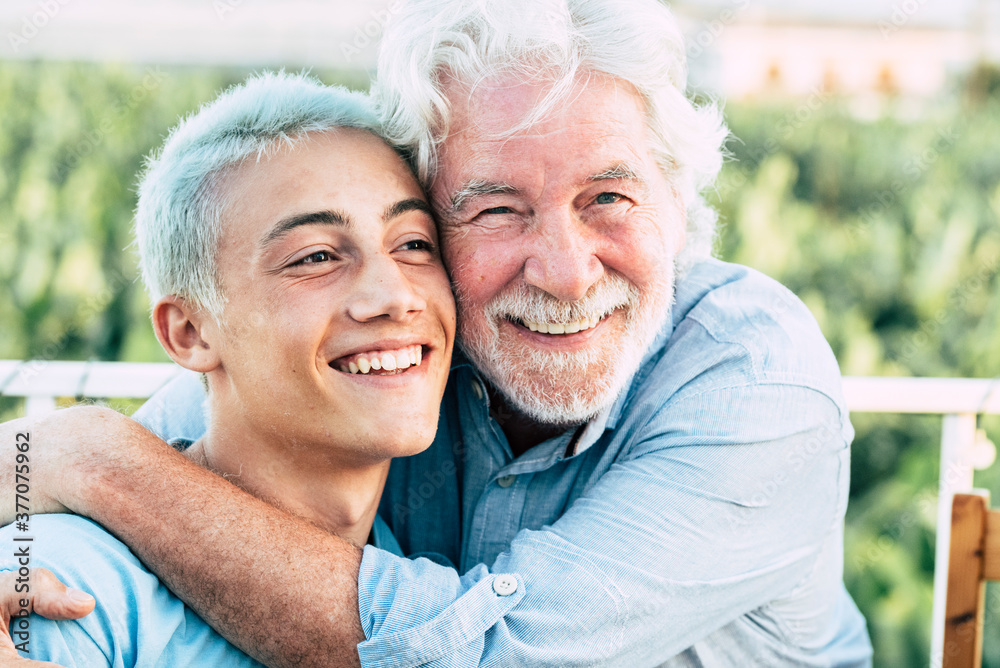 Grandfather's day concept with old handsome senior man and young boy grandson hug and enjoy together the family and the beautiful day - concept of different ages and elderly life - white hair both 