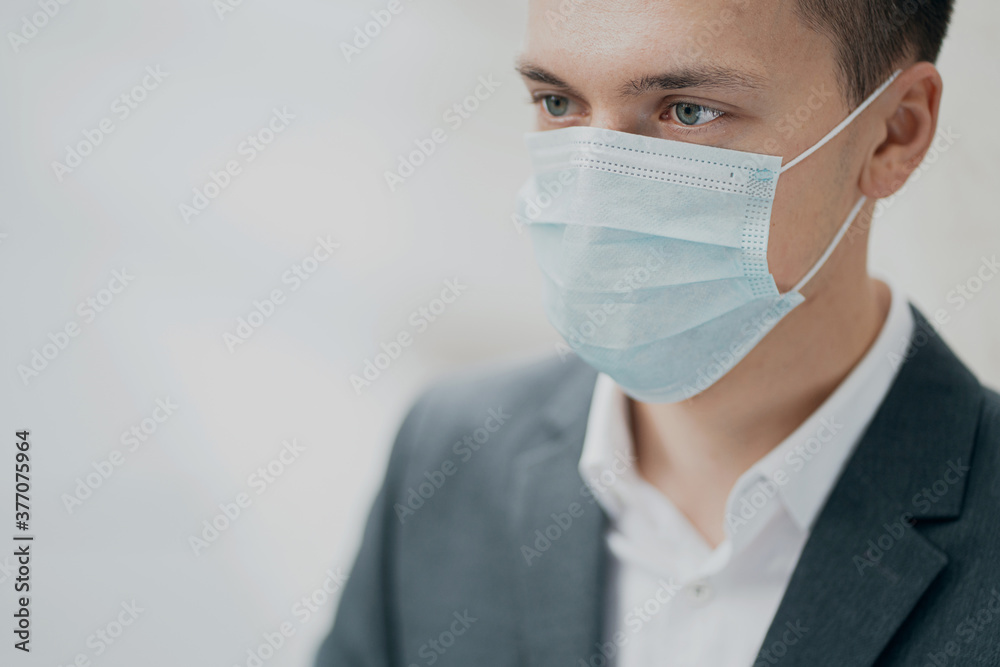 blue protective mask from the pandemic on the face. portrait of a serious smart man Manager holding a new phone calls the Director talks about the completed project. look away blue protective mask from the pandemic on the face. portrait of a serious smart man Manager holding a new phone calls the Director talks about the completed project. look away
