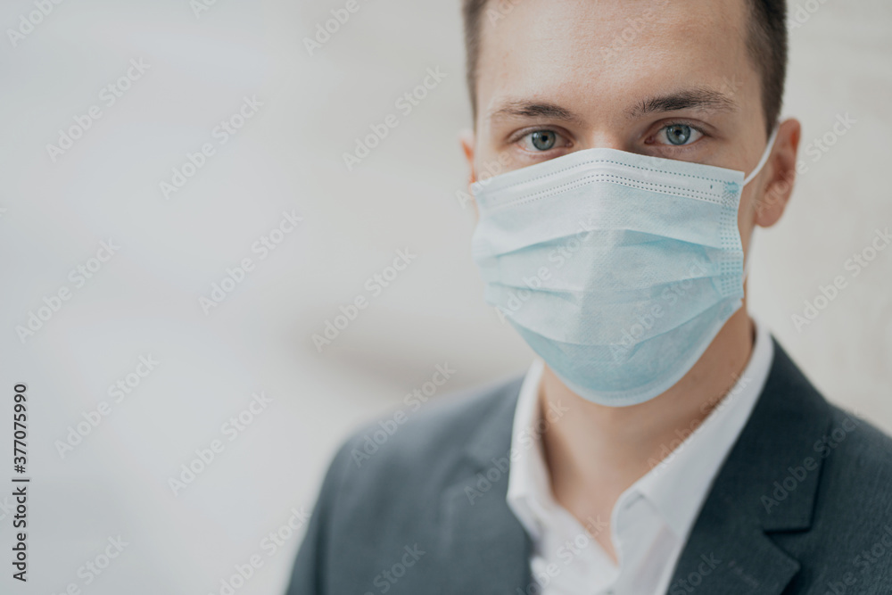 blue protective mask from the pandemic on the face. portrait of a serious smart man Manager holding looking at the camera, thinking about health blue protective mask from the pandemic on the face. portrait of a serious smart man Manager holding looking at the camera, thinking about health