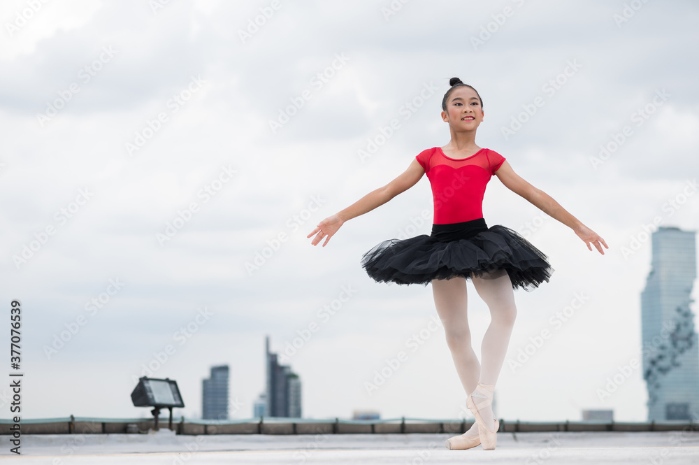 Asian ballerina girl dancing on the rooftop of the building city background.