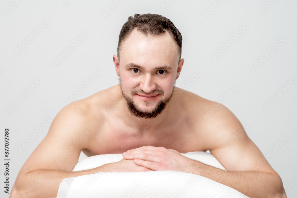 Young caucasian man lying on front on table spa, waiting for beauty treatment and looking at camera Young caucasian man lying on front on table spa, waiting for beauty treatment and looking at camera