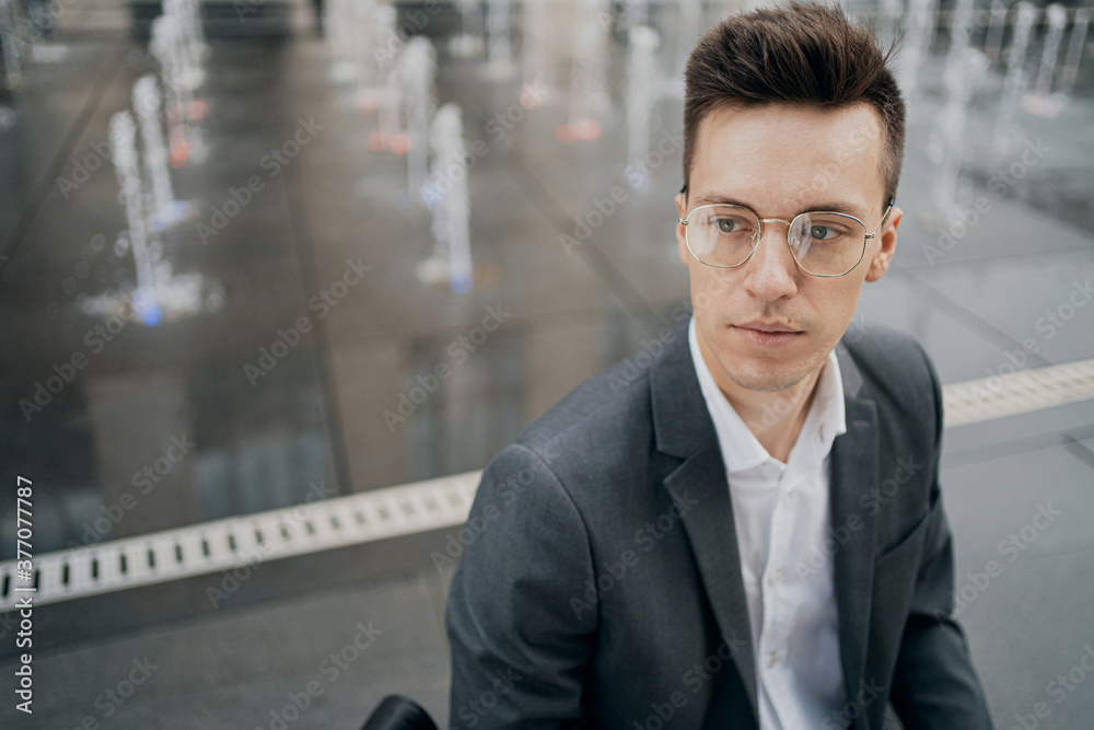 portrait of Caucasian appearance, holding a laptop. gray business suit, glasses on his face. it is located near the business center. look away portrait of Caucasian appearance, holding a laptop. gray business suit, glasses on his face. it is located near the business center. look away