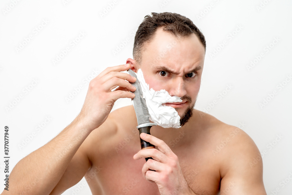 Young caucasian man shaving beard with knife on white background Young caucasian man shaving beard with knife on white background