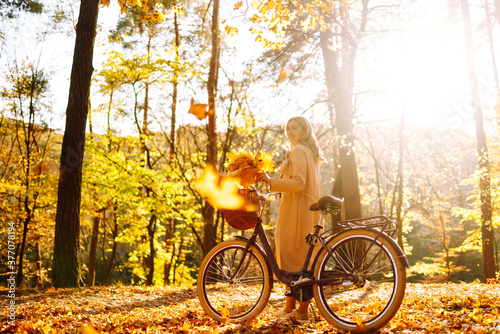 Autumn woman in autumn park. Happy young woman posing with bike in autumn forest.