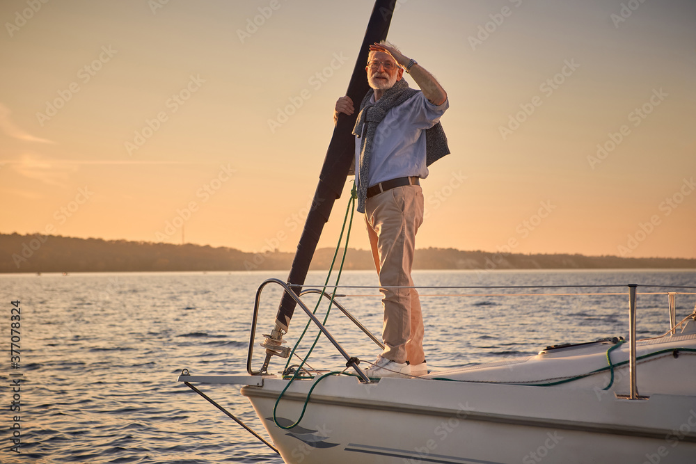 Sailing man on yacht. Elegant senior man standing on the side of a sailboat or yacht deck floating in sea, looking at the horizon and enjoying amazing view