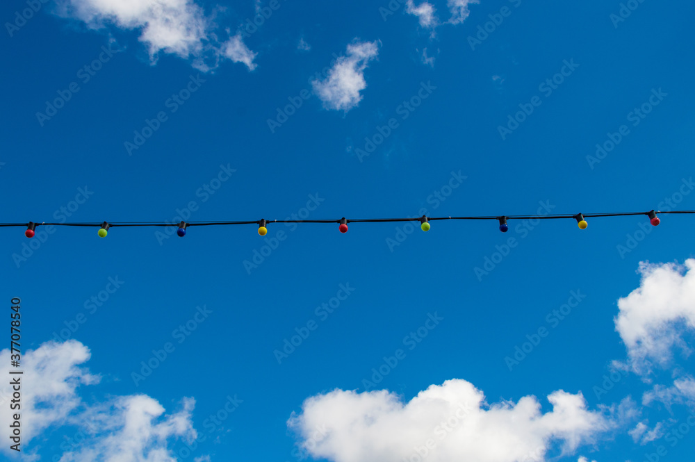 electric lamp garland on blue sky with clouds background electric lamp garland on blue sky with clouds background